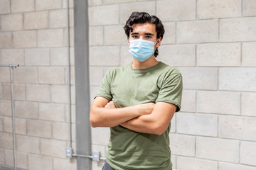 Young man with mouth mask alone in building under construction.