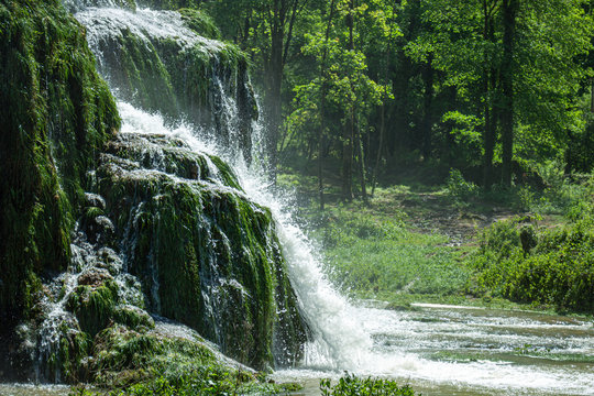 Beaumes-les-Messieurs tuffs waterfall. Rock covered with moss in a natural site. Jura - France.