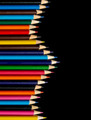 Multi-coloured colouring pencils isolated on a black background with copy space