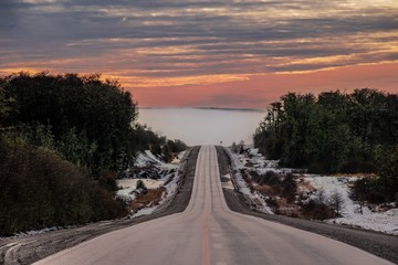 ruta con atardecer, neblina y nieve, ruta desolada.