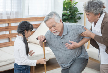 Asian grandfather fall down grandmother and granddaughter help and support carry him to sit on sofa,retirement life concept.