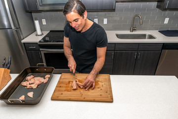 Prepping chicken breast on a cutting board inside a home kitchen