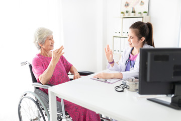 Fototapeta premium Asian doctor talk with old female patient about disease symptom, they show okay sign with hand together, elderly health check up, happiness hospital