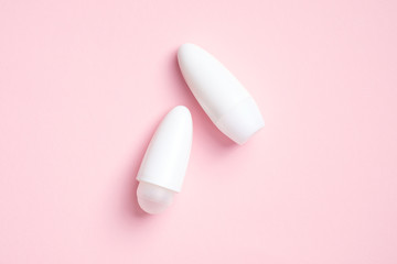 Blank deodorant bottles on pink background. Antiperspirant packaging mockups. Flat lay, top view