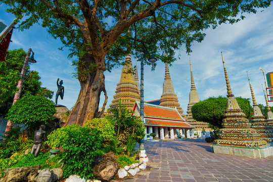 Thai ancient artistic architecture in Wat Poh with stupa complex and statue on sunny day and beautiful sky , Bangkok Thailand.
