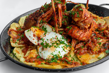 Formentera Lobster with fried potatoes, eggs and parsley in a traditional paella pan. Caldereta de bogavante de Formentera