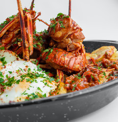 Formentera Lobster with fried potatoes, eggs and parsley in a traditional paella pan. Caldereta de bogavante de Formentera