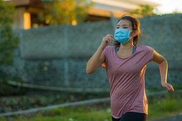 Naklejka premium Asian woman in anti pollution face mask running workout - young dedicated chinese girl jogging at beautiful city park on sunset enjoying fitness in covid-19 pandemic times