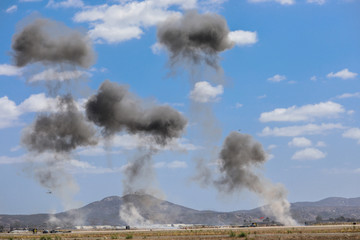 Giant outdoors explosion with fire and black smoke with mountain on the background