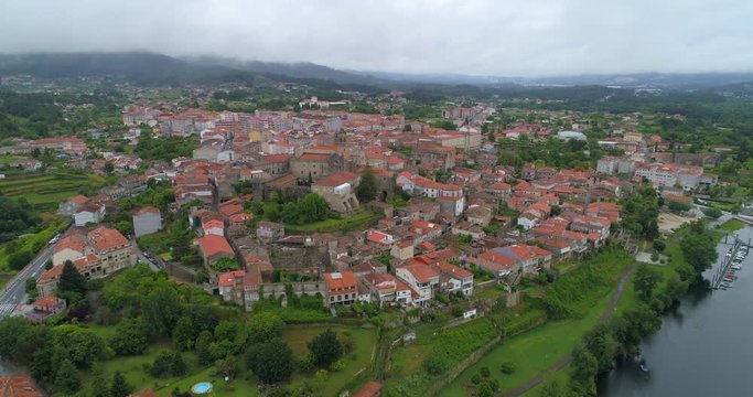 Aerial shot of the Playa de la Marina moving towards the buildings in the town of Tui, Spain on an overcasted day