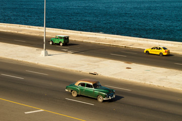 Panoramic view of highway in Cuba with ocean view and three cars