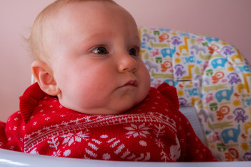 Portrait of little cute baby sitting in highchair and looking around