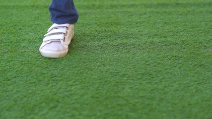 Close up grass and shoes of kid jogging and jump on grass field - Powered by Adobe