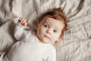 Closeup portrait of cute Caucasian newborn baby. Adorable funny child infant with blue grey eyes...