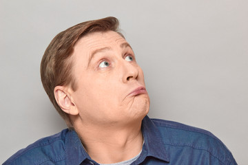 Naklejka premium Portrait of blond mature man with silly perplexed expression on face