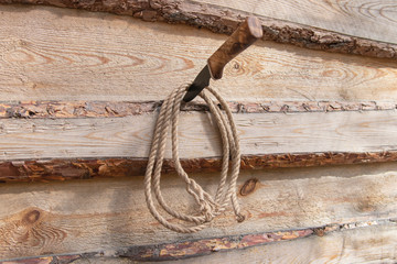 A knife in a wooden wall on which a twisted rope hangs.