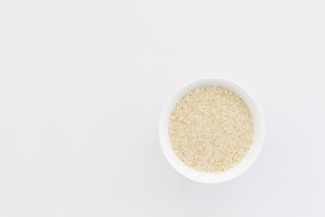 Dry rice in a bowl isolated om a white background with copy space