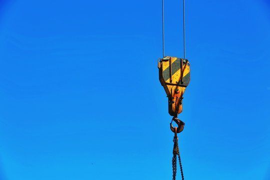 Low Angle View Of Crane Hook Against Clear Blue Sky