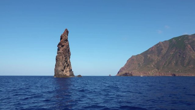 Rocks in Mediterranean sea against horizon and Lipari Island. Blue sky, summer sunny day. Sicily, Italy