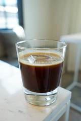 Close up glass of iced black Americano coffee on white table