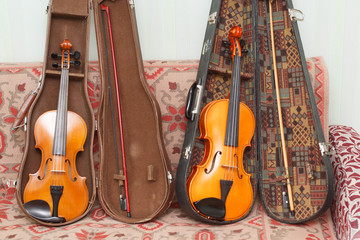 Naklejka premium Two yellow-orange violins of a different sizes with bows and cases 