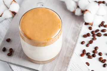 Trending Korean drink - dalgona coffee. A glass of ice milk with sweet whipped foam on a light background.