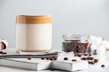 Trending Korean drink - dalgona coffee. A glass of ice milk with sweet whipped foam on a light background.