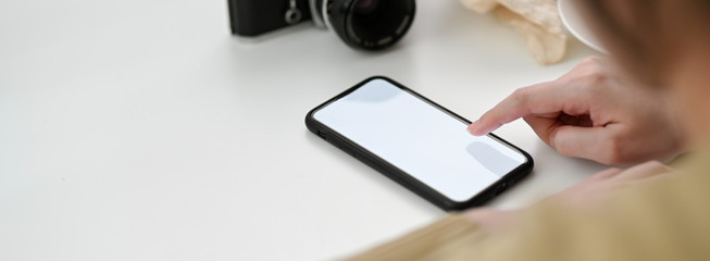 Close up view of female freelancer using mock-up smartphone to relax