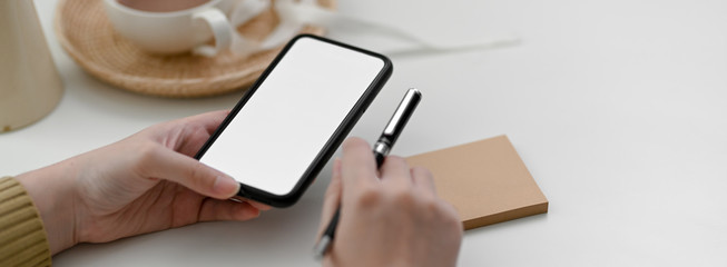 Close up view of female freelancer using mock-up smartphone to contact customer