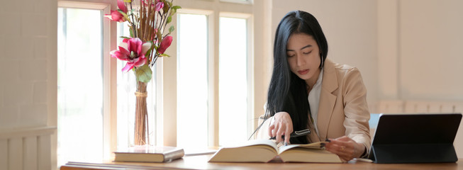 Cropped shot of professor reading book to prepare her teaching in teacher’s room