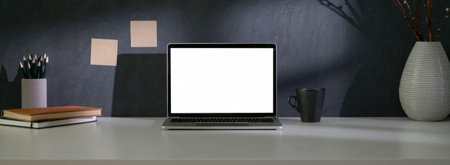 Close up view of trendy workspace with mock-up laptop, plant vase and copy space