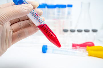 Naklejka premium The hands of the researcher holding a centrifugal tube containing red liquid