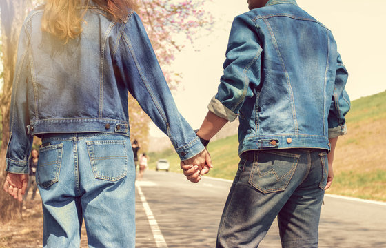 Couples wearing blue jeans hold hands to travel.