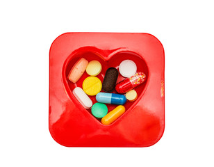 Different pills in box in the shape of a heart. Isolated on white.