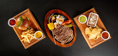 Roasted flank steak with chilies and baked potato, spicy wings and BBQ, hamburger with meat and cheese
