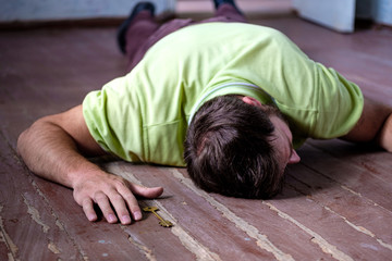a white man is on the floor in a dirty apartment next to the hand key