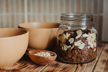 Oatmeal in a wooden spoon on a wooden background and dried fruit in a glass jar. The concept of a...