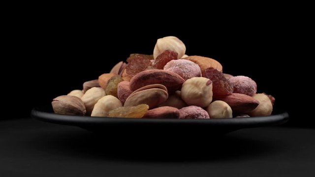 Mixed nuts grains of spin around themselves on a black background and ground