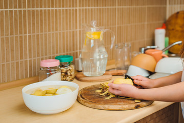 The child`s hands perform peeling potatoes using a vegetable peeler. Speciale quipment for cleaning vegetables .
