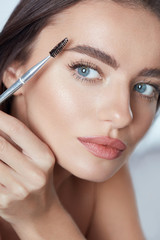 Eyebrow Makeup. Woman Brushing Brows With Brush. Beautiful Girl With Blue Eyes And Perfect Skin Close Up Portrait.
