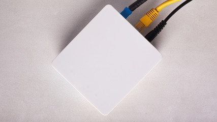 Wi-Fi router modem with connected cables on a white background close-up top view