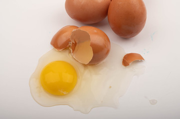 A broken chicken egg and scattered eggs on a white background. Close up.