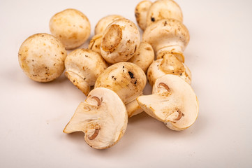 Halves of cut young mushrooms and young mushrooms scattered on a white background. Close up.