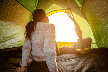 The woman asian who just woke up inside the tent was watching the sunrise in the morning as a...