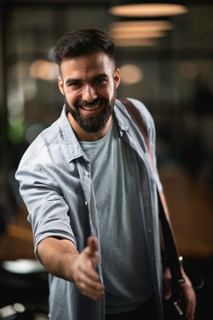 Businessman giving a handshake in office. Handsome man at work.	