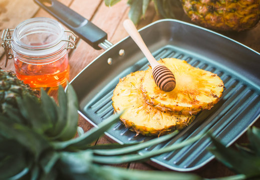 Close-up Of Honey Dipper And Pineapple Slices In Cooking Pan