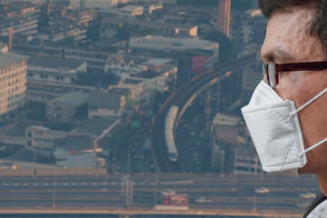 A senior man wearing medical mask to prevent corona virus, Covid-19 pandemic in city and transportation background