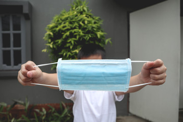 boy on white shirt holding madical face mask in hands
