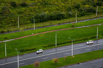 Cars on the road in the urban space among the greenery. The view from the top. Going out of town on vacation.