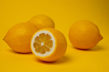 Ripe and juicy lemons shot on a yellow background. Background for vitamins and fruits.
